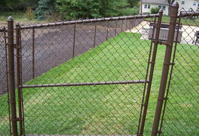 A yard in Batavia, IL features a chain link fence and a gate
