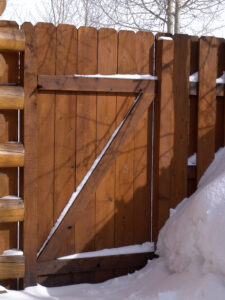 A wooden fence and gate adjacent to a snow-covered wall in Batavia, IL
