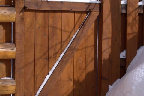 A wooden fence and gate adjacent to a snow-covered wall in Batavia, IL